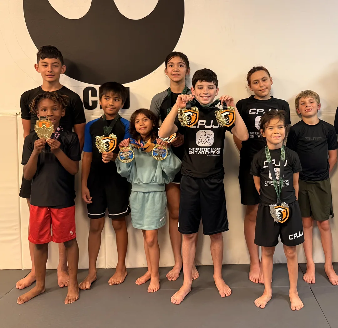 The CPJJ kids travel team holding up the medals they won at jiu jitsu competitions